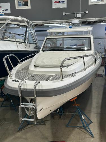 Nimbus W9 2021 Nimbus W9 boat in showroom, front view with metal railings and ladder.