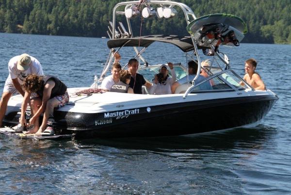 MasterCraft X10 2004 MasterCraft X10 boat with people enjoying a sunny day on the lake.