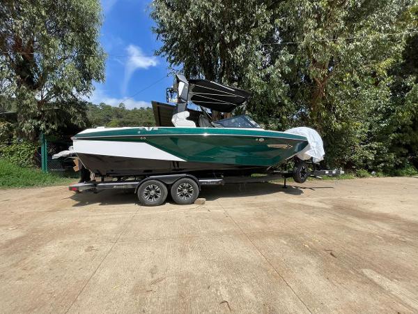 Nautique Super Air G23 2023 Nautique Super Air G23 boat on a trailer, surrounded by trees.