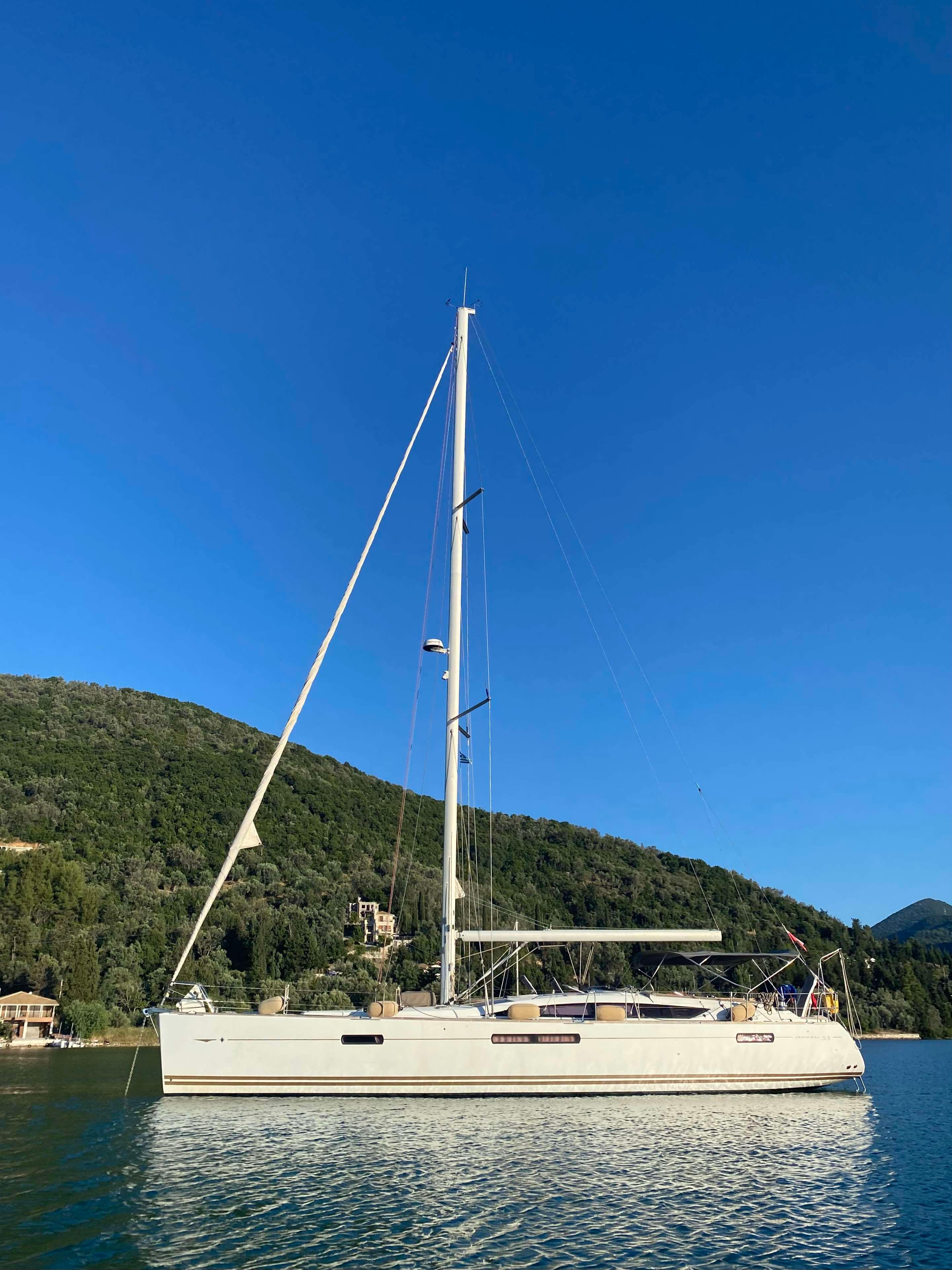 Jeanneau 53 Sailing yacht Jeanneau 53, 2010 model, anchored on calm water with scenic hillside backdrop.