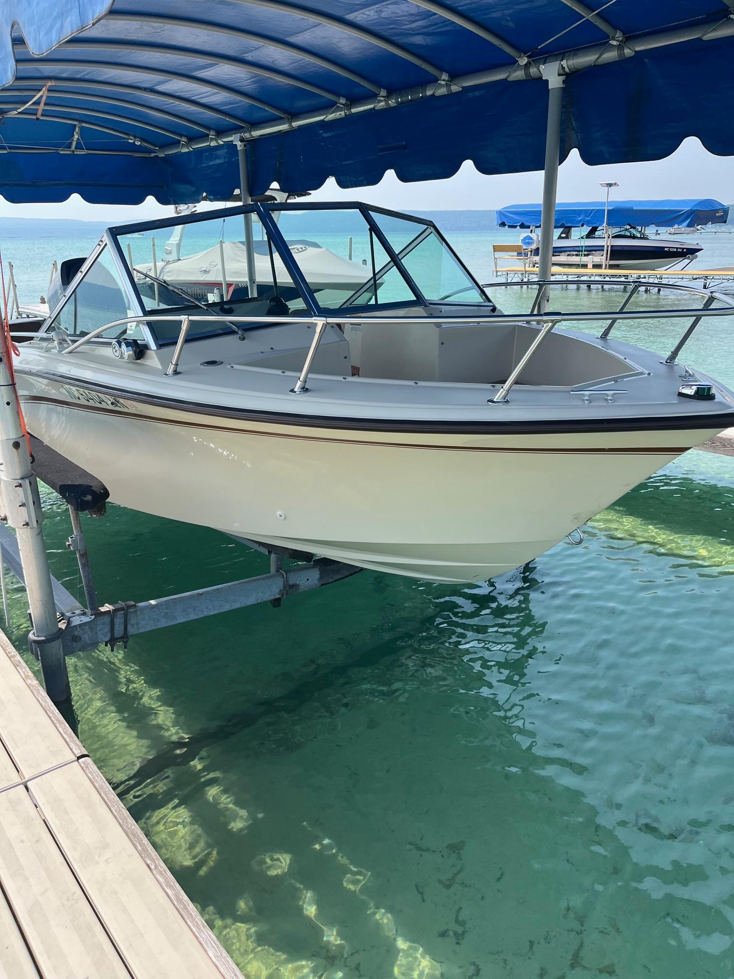 Grady-White 190 1983 Grady-White 190 boat on lift, under blue canopy, over clear water.