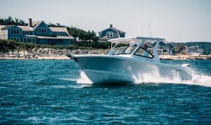Edgewater 262CX Crossover Edgewater 262 CX 2025 boat cruising near coastal homes on a sunny day.