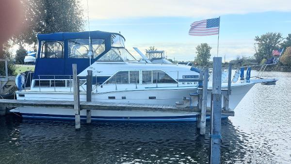 Chris-Craft 350 Catalina 1986 Chris-Craft 350 Catalina docked, featuring blue canopy and American flag.