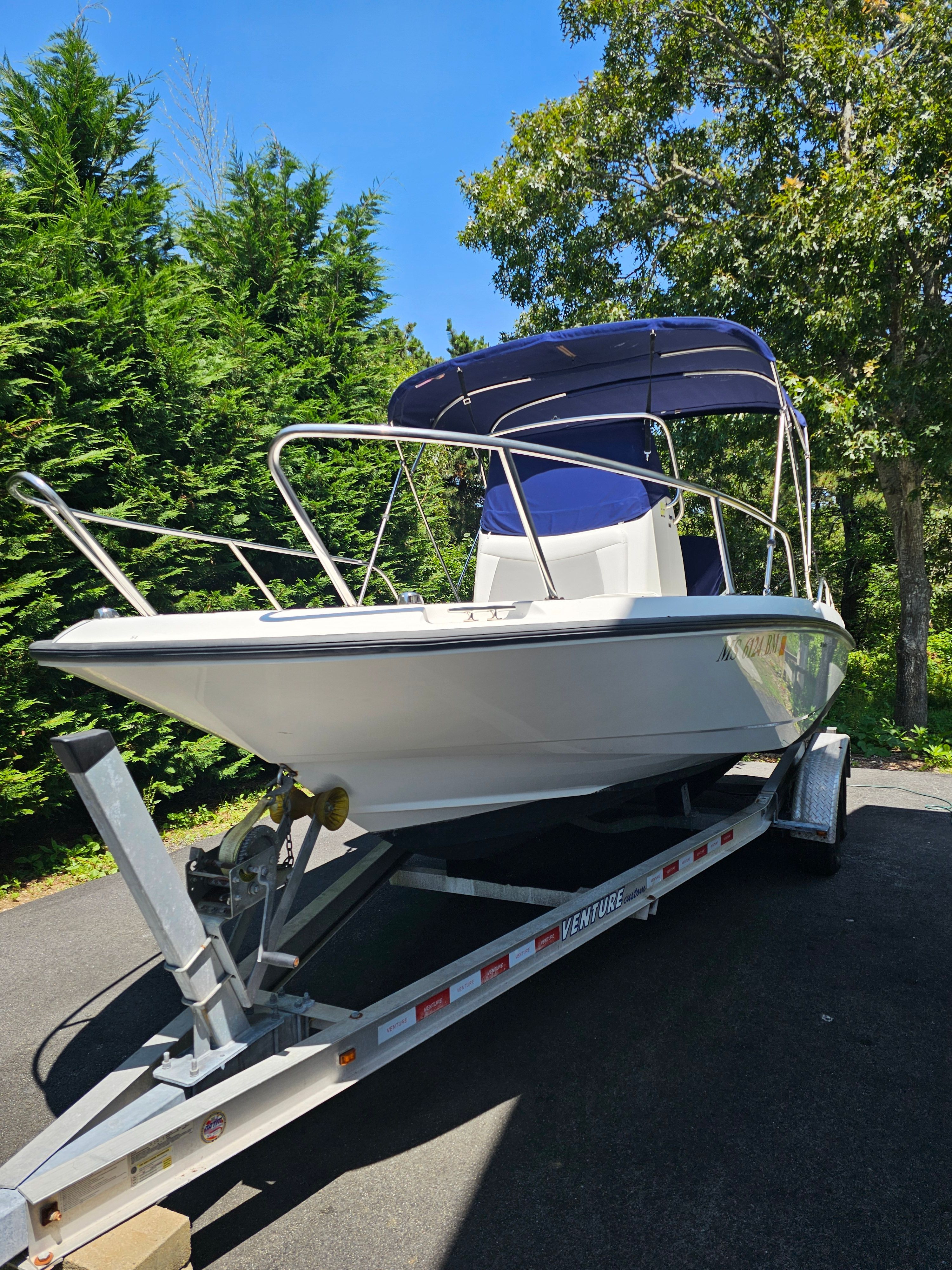 Boston Whaler 210 Dauntless 2014 Boston Whaler 210 Dauntless boat on trailer, surrounded by trees.