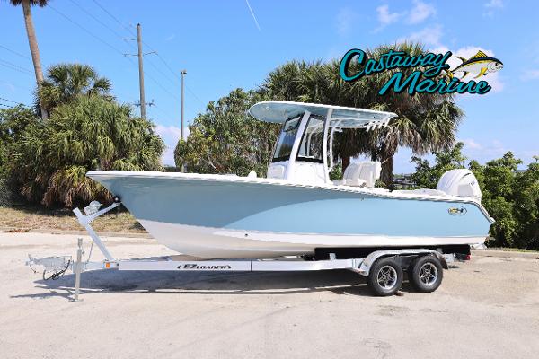 Sea Hunt Ultra 239 SE 2025 Sea Hunt Ultra 239 SE boat on trailer, parked outdoors, with palm trees in background.