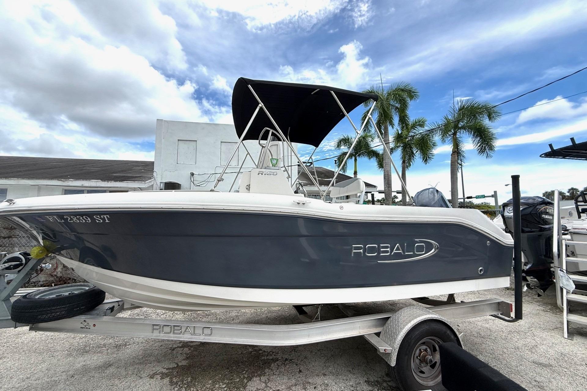 Robalo R180 Center Console 2020 Robalo R180 Center Console boat on trailer, under cloudy sky with palm trees.