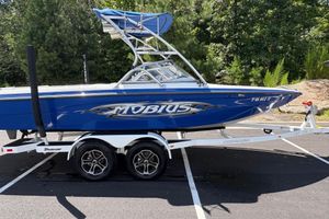 Moomba MOMBIUS LS 2004 Moomba MOBIUS LS boat on trailer, blue with tower, parked outdoors.