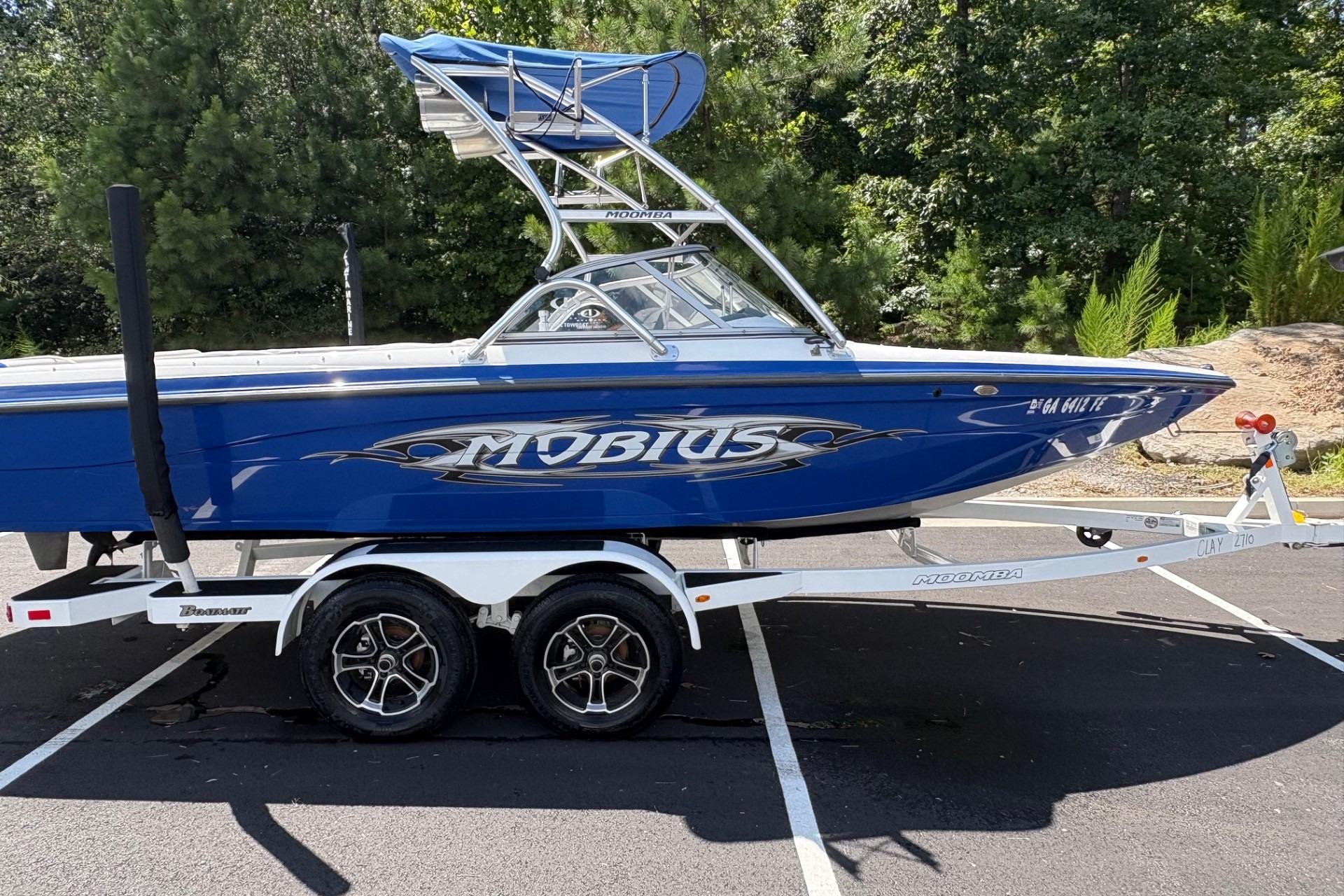 Moomba MOMBIUS LS 2004 Moomba MOBIUS LS boat on trailer, blue with tower, parked outdoors.