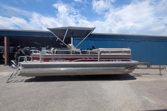 Sun Tracker SportFish 22 DLX 2022 Sun Tracker SportFish 22 DLX pontoon boat parked outdoors under a blue sky.