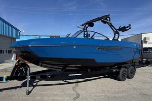 Moomba Tykon 2026 Moomba Tykon boat in blue on a trailer, parked outdoors.