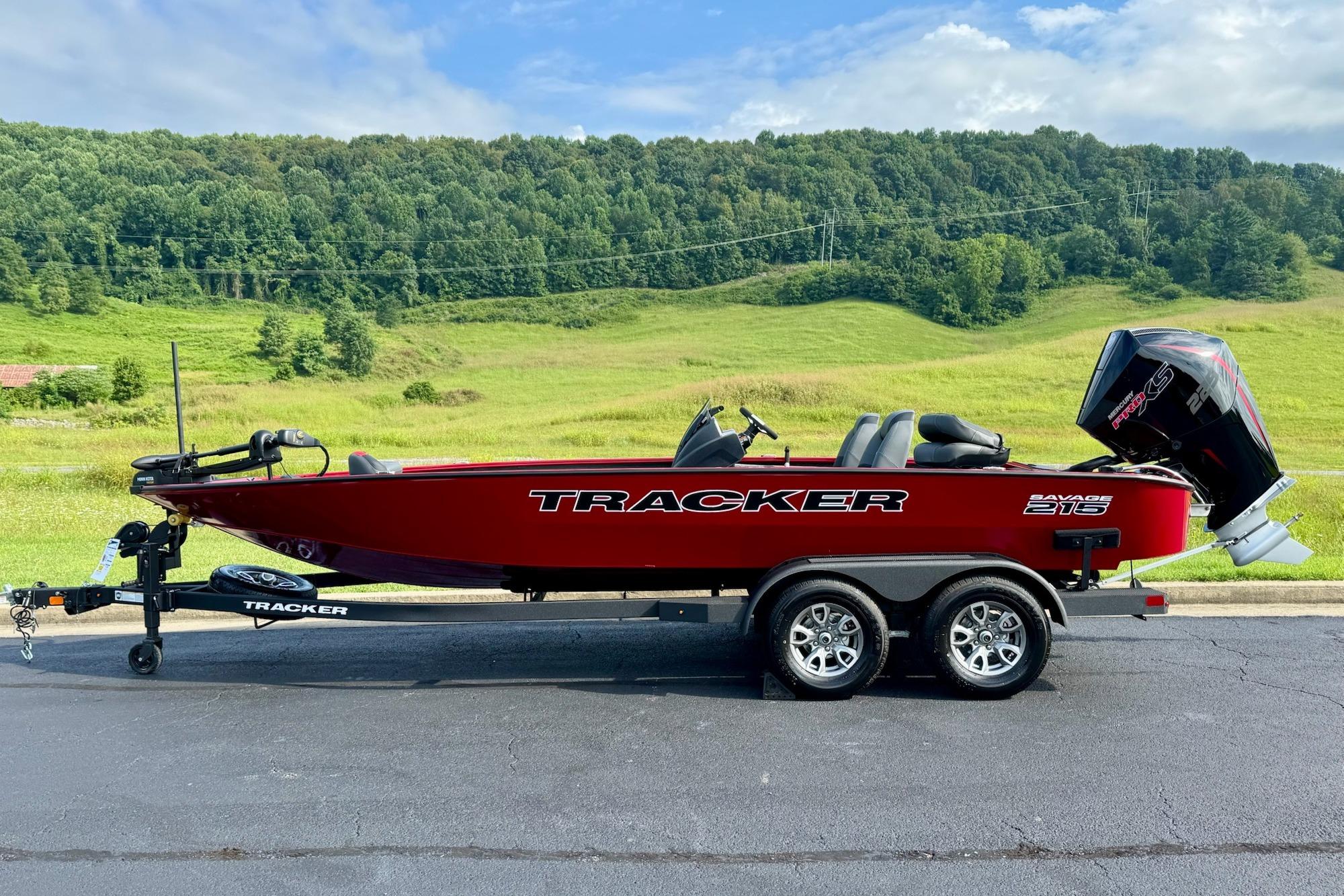 Tracker Savage 215 2026 Tracker Savage 215 boat on trailer, set against a lush green landscape.