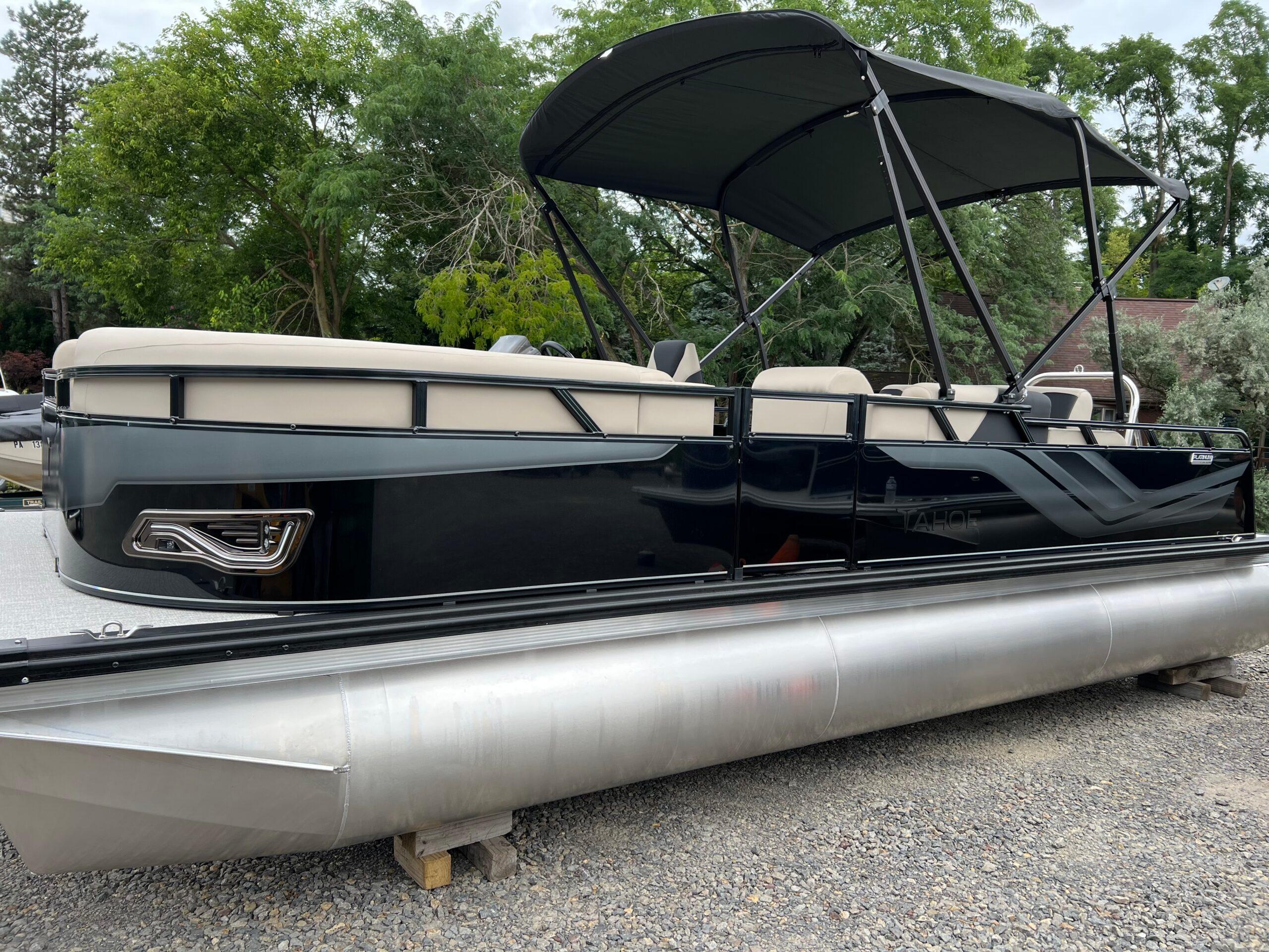 Tahoe Pontoon 2385 VRB 2026 Tahoe Pontoon 2385 VRB with canopy, parked on gravel, surrounded by trees.
