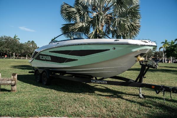 Scarab 255 2022 Scarab 255 boat on a trailer in a grassy park with palm trees.