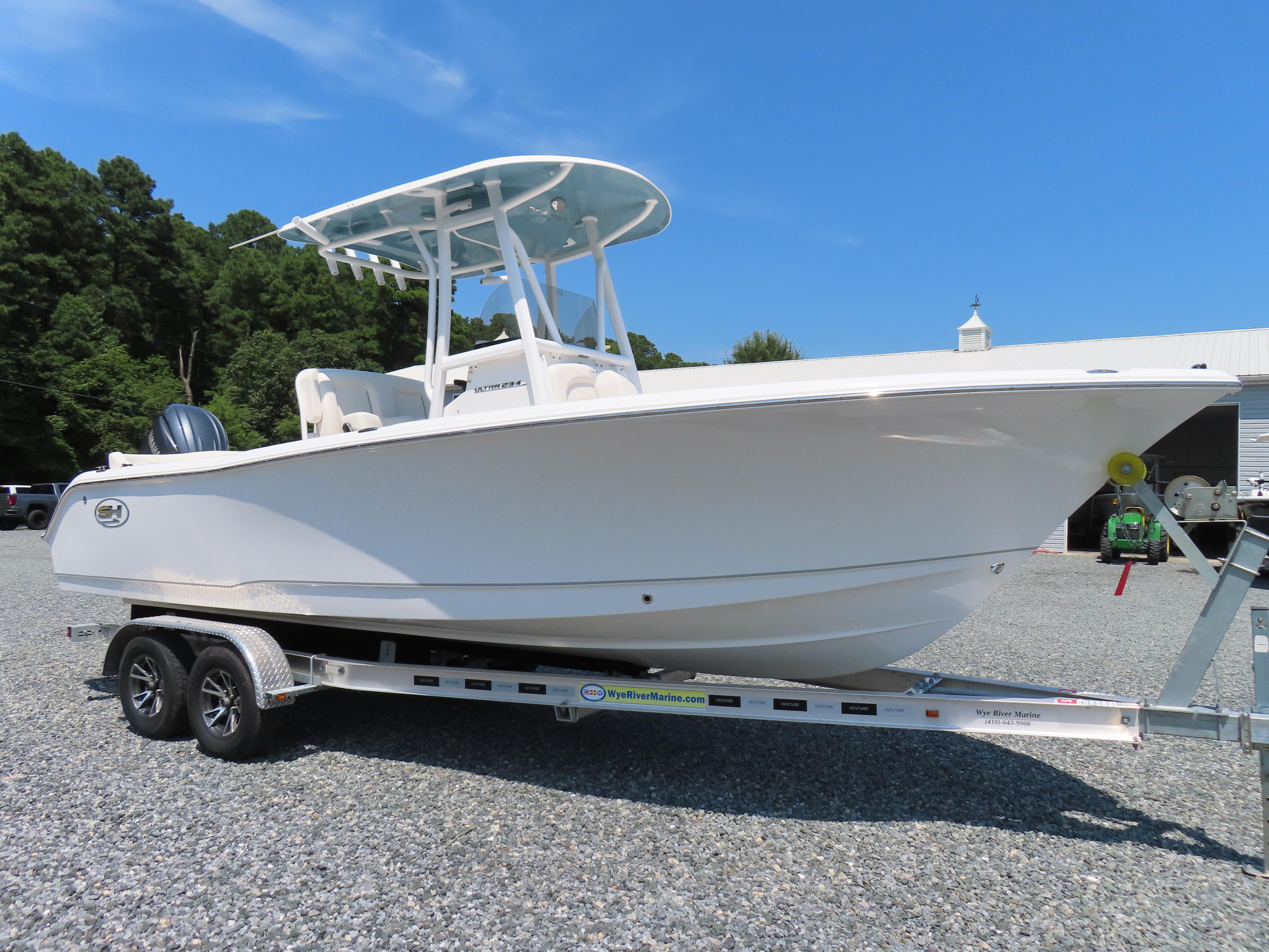 Sea Hunt Ultra 234 2024 Sea Hunt Ultra 234 boat on trailer, parked outdoors under clear blue sky.