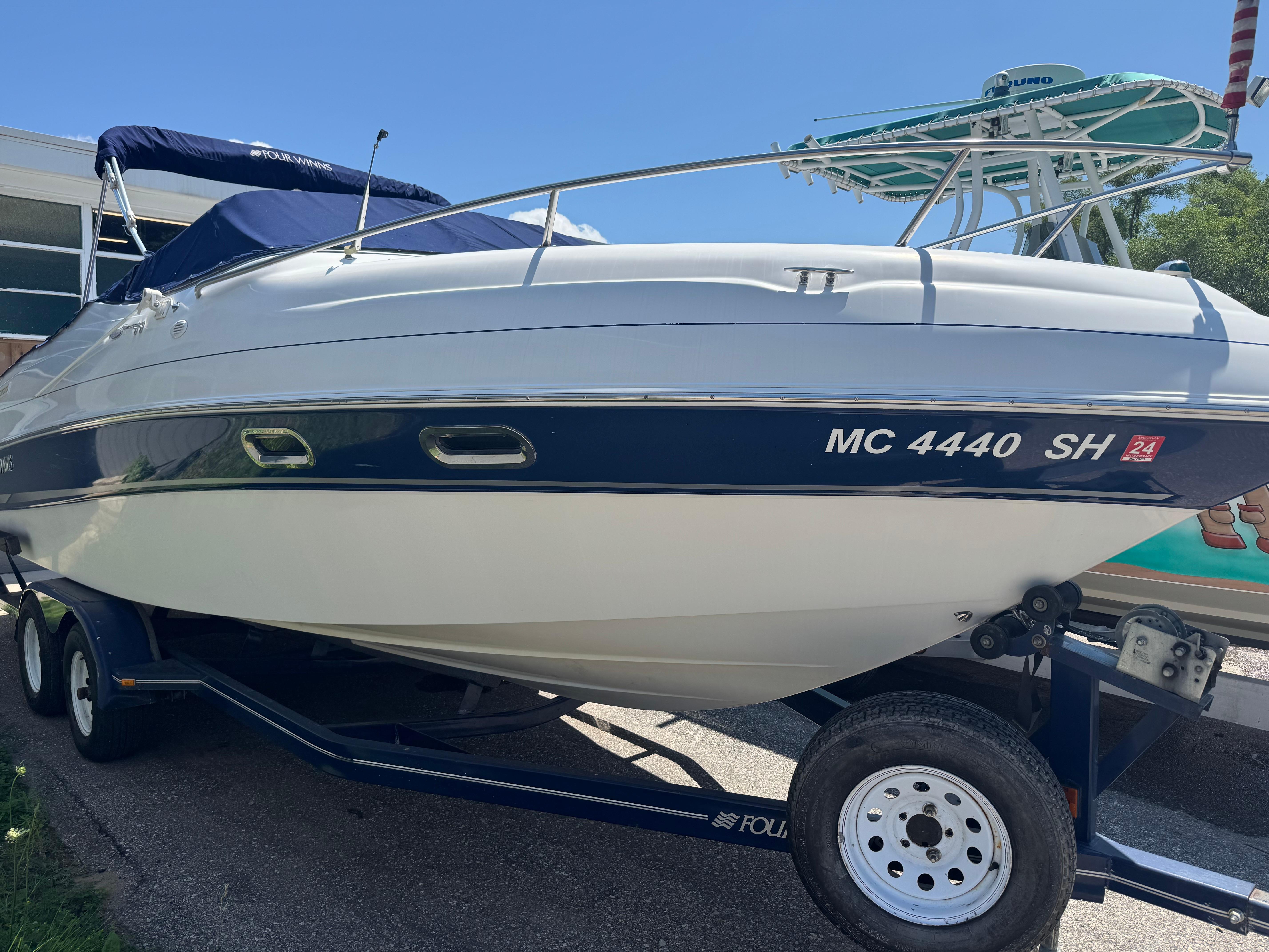 Four Winns 245 Sundowner 2002 Four Winns 245 Sundowner boat on trailer, side view, with blue and white exterior.