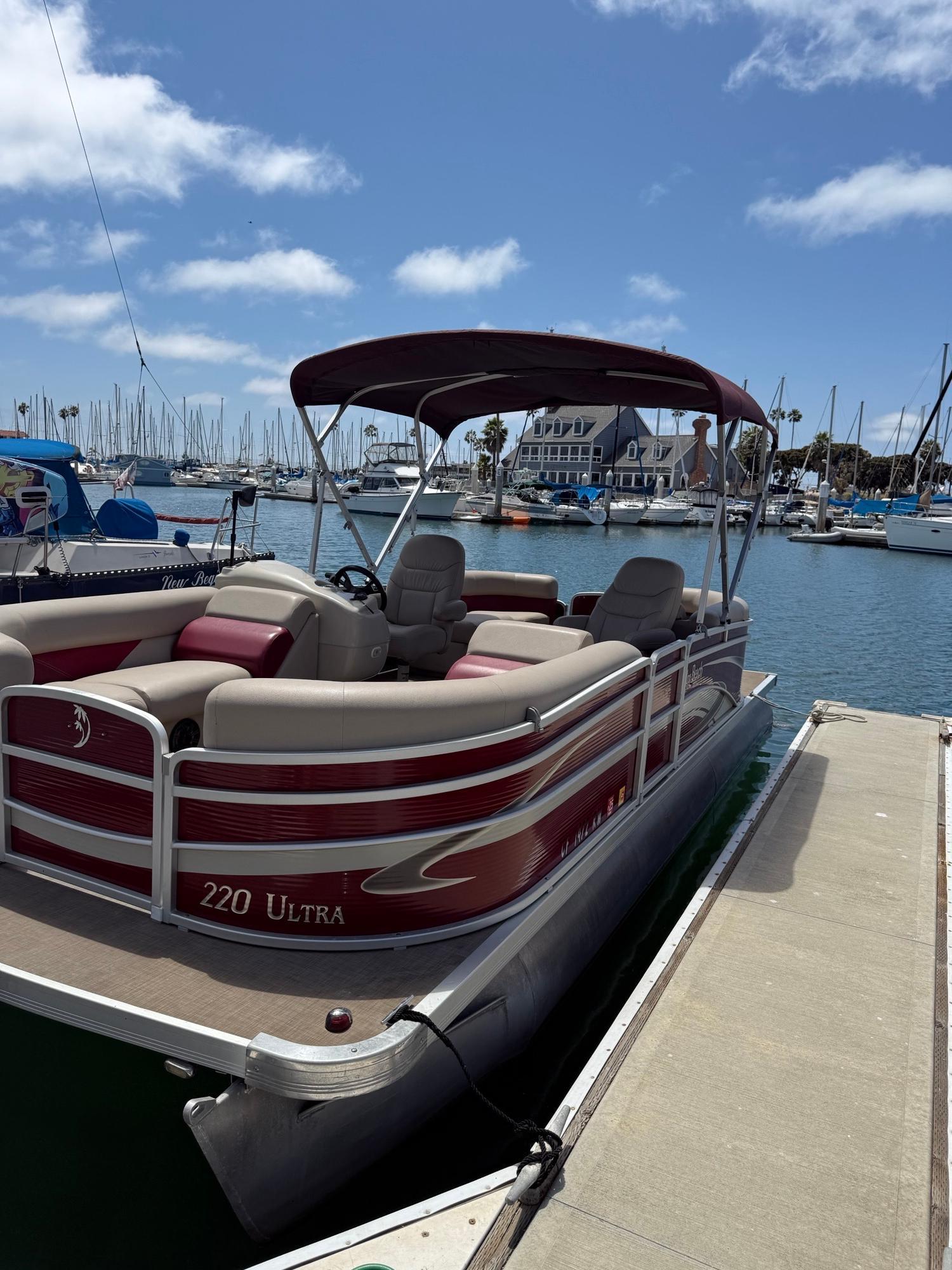 Premier Palm Beach 2016 Premier Palm Beach pontoon boat docked in a marina under a clear blue sky.