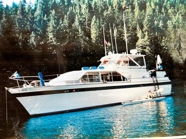 Chris-Craft Constellation 1963 Chris-Craft Constellation yacht on serene water with forest backdrop.