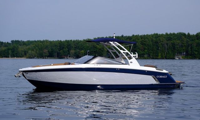 Cobalt R8 Surf 2025 Cobalt R8 Surf boat on a serene lake with forested background.