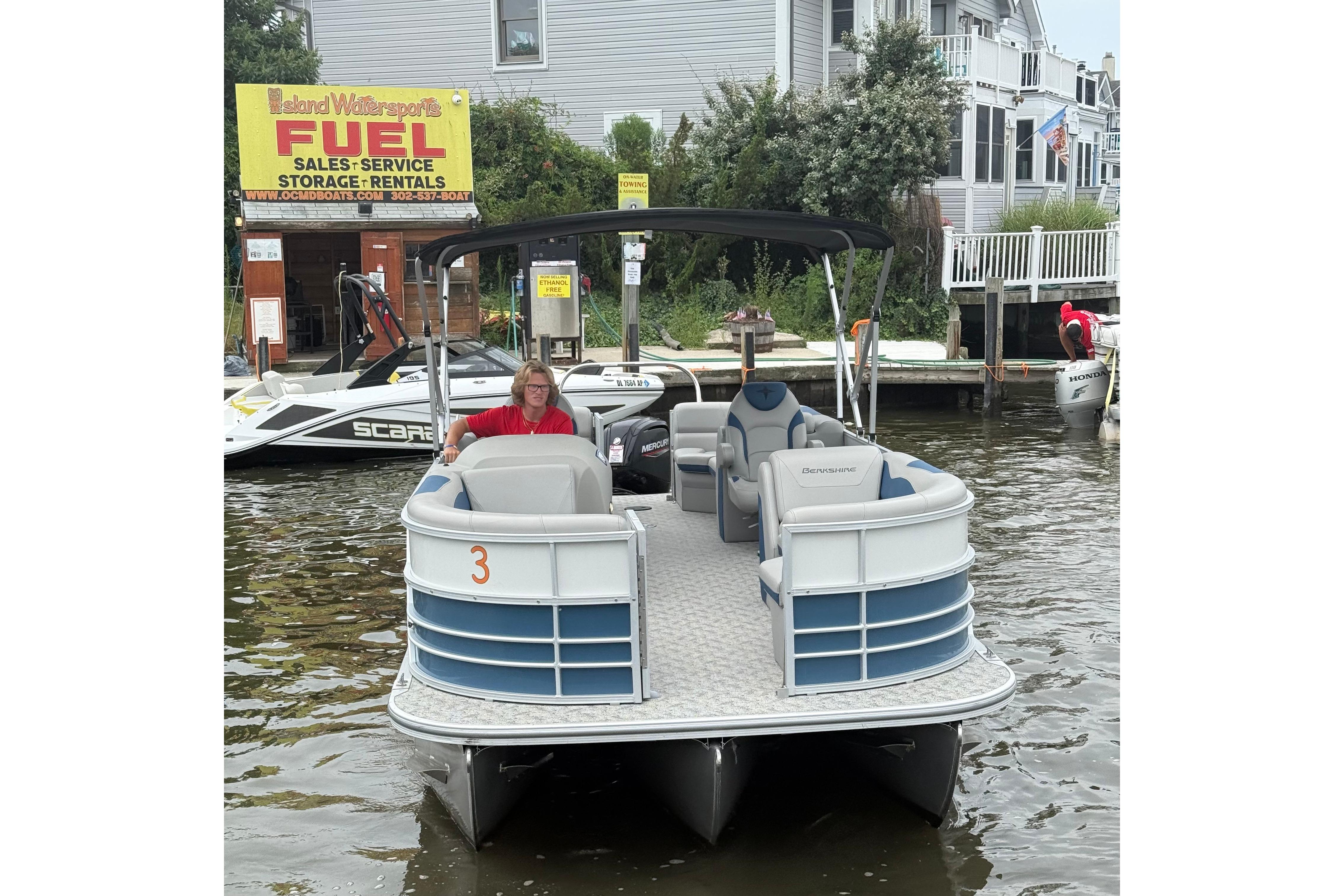 Berkshire 24RFX LE 2.75 2025 Berkshire 24RFX LE 2.75 pontoon boat docked near waterfront rental shop.