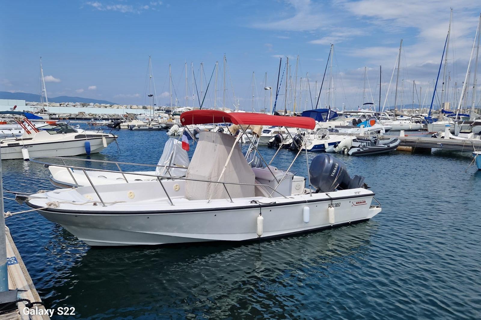 Boston Whaler 21 Outrage 1996 Boston Whaler 21 Outrage boat docked in a marina with a red canopy.