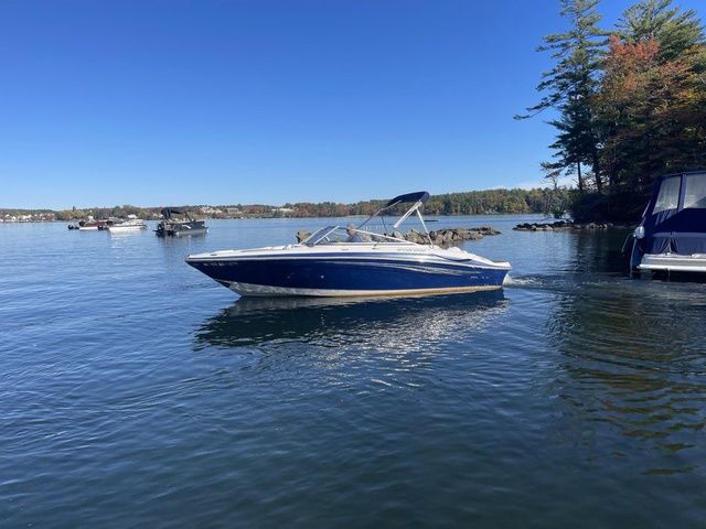 Four Winns H220 2011 Four Winns H220 boat on a calm lake under a clear blue sky.