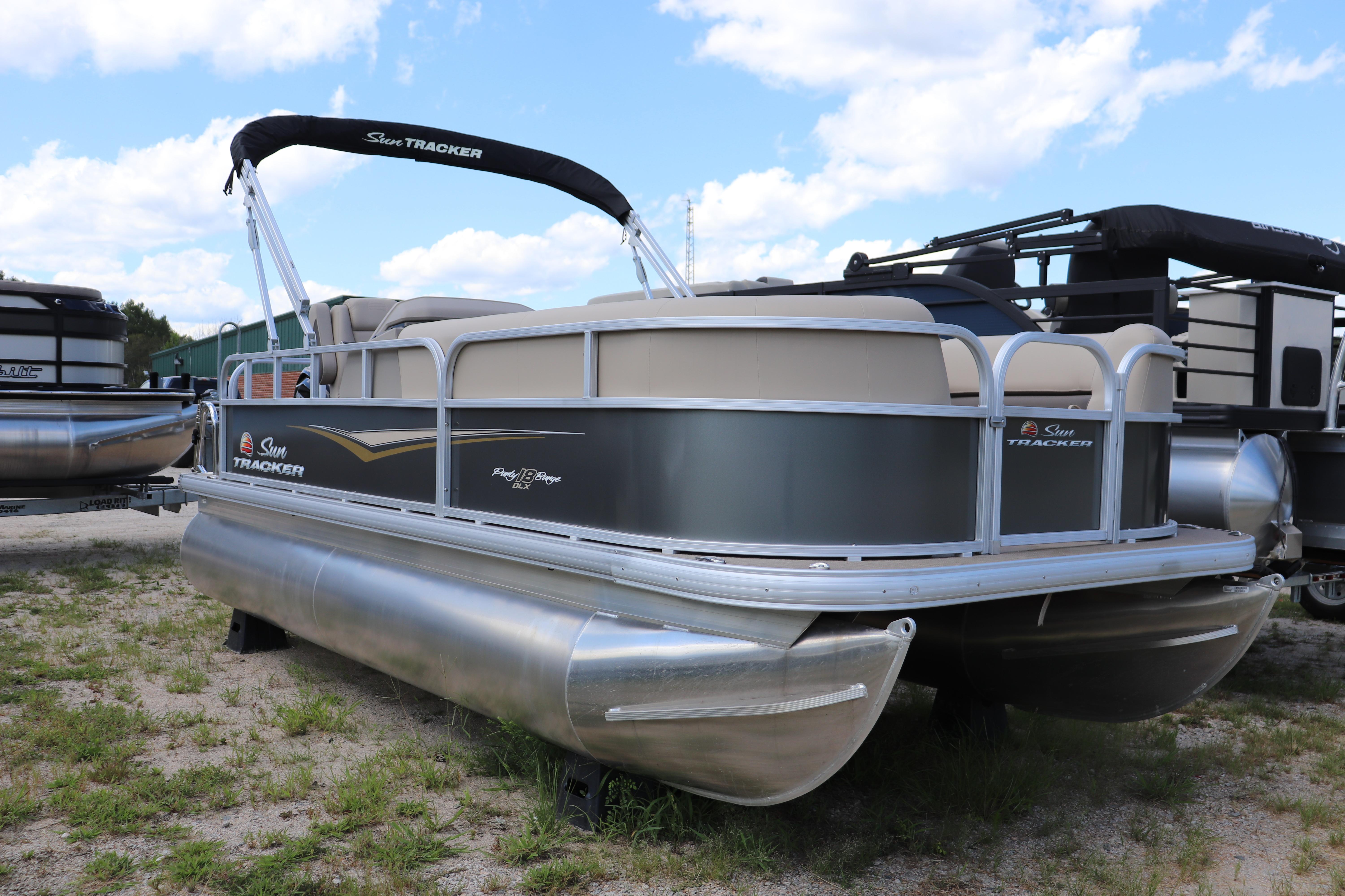 Sun Tracker Party Barge 18 DLX 2025 Sun Tracker Party Barge 18 DLX pontoon boat on grassy terrain under blue sky.