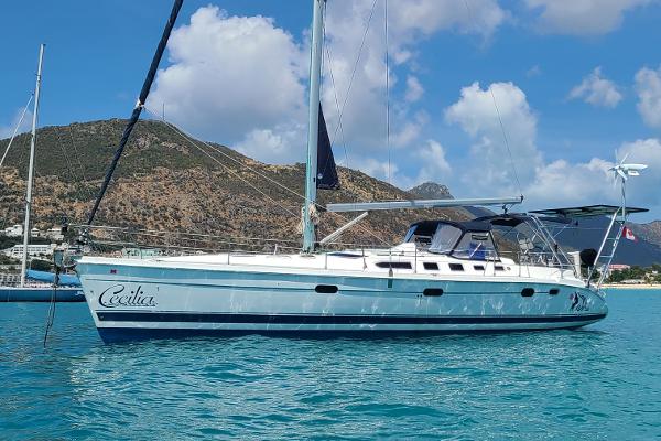 Hunter 46 2006 Hunter 46 sailboat anchored in clear blue water with scenic mountain backdrop.