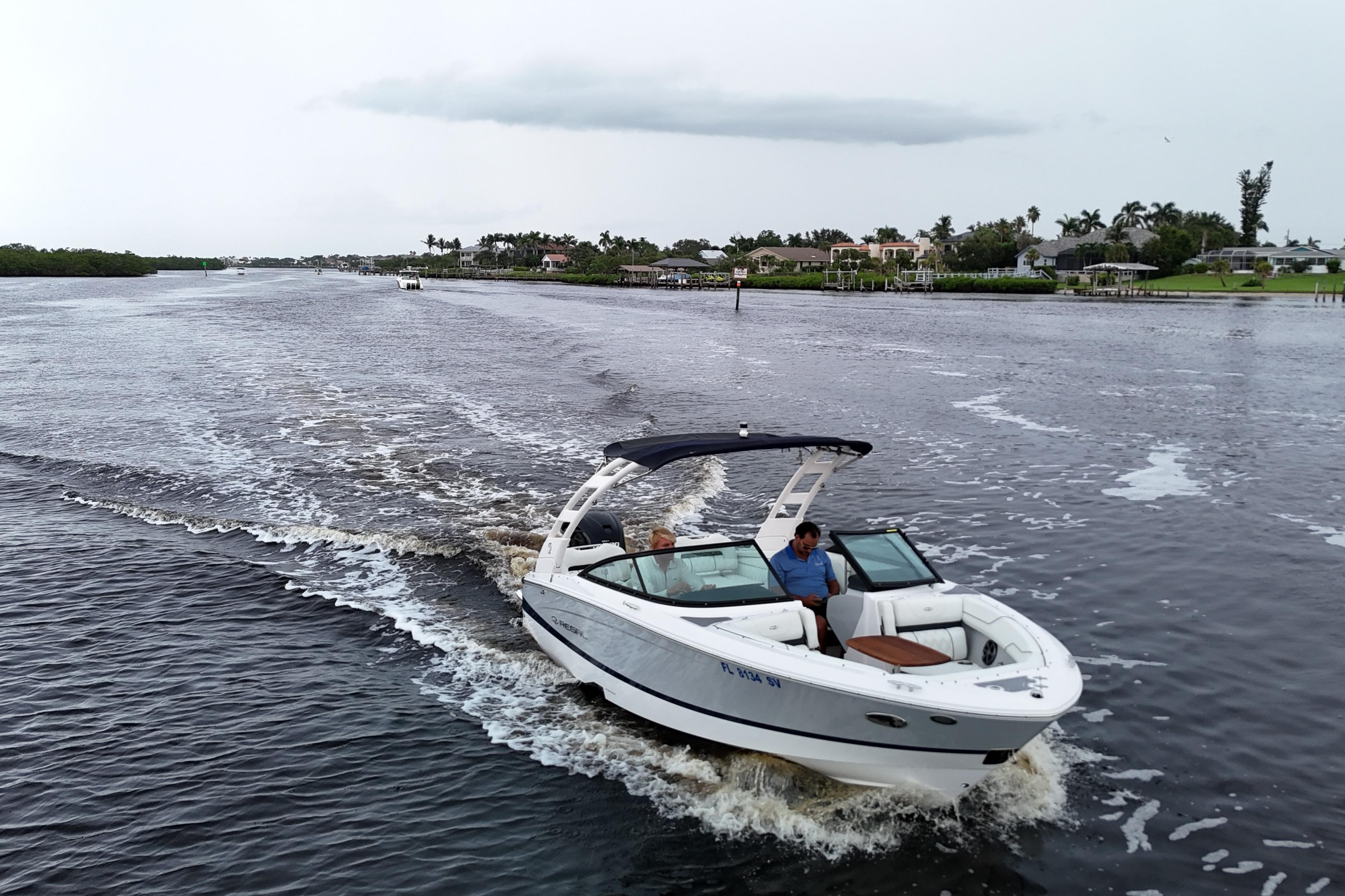 Regal LX2 2021 Regal LX2 boat cruising on a scenic waterway with lush greenery.