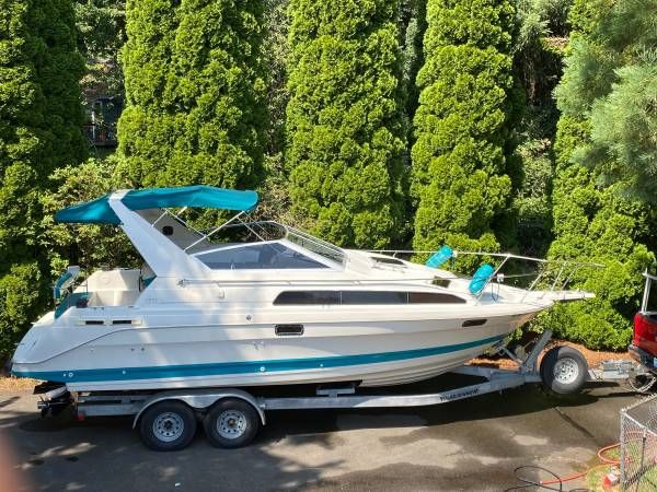Bayliner 2855 Ciera Bayliner 2855 Ciera 1993 boat on trailer, surrounded by lush green trees.