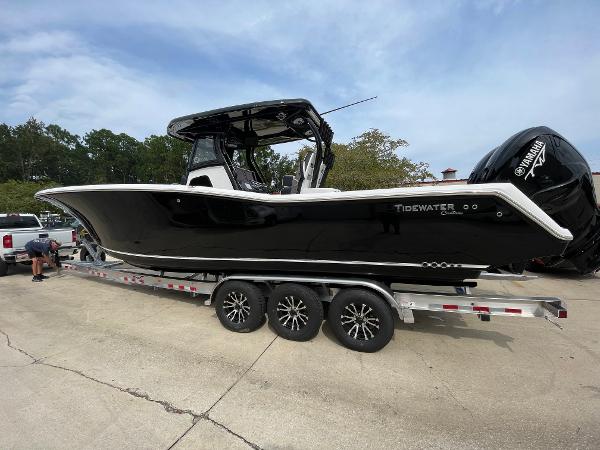 Tidewater 320 CC Adventure 2023 Tidewater 320 CC Adventure boat on a trailer, black hull, triple-axle wheels.
