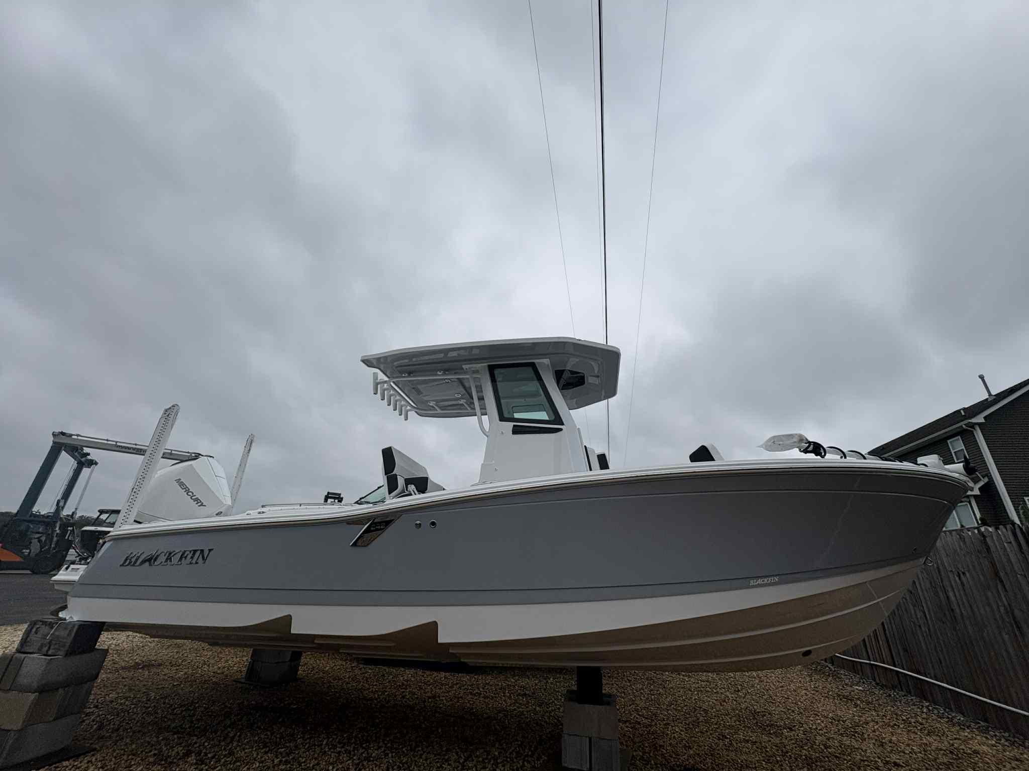 Blackfin 242HB 2026 Blackfin 242HB boat on blocks under cloudy sky.