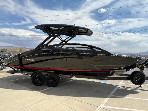 Yamaha Boats 275 SD 2025 Yamaha Boats 275 SD, sleek black design, parked on a trailer under a cloudy sky.