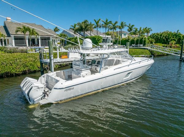 Intrepid 407 Cuddy 2020 Intrepid 407 Cuddy boat docked near waterfront homes, surrounded by lush greenery.