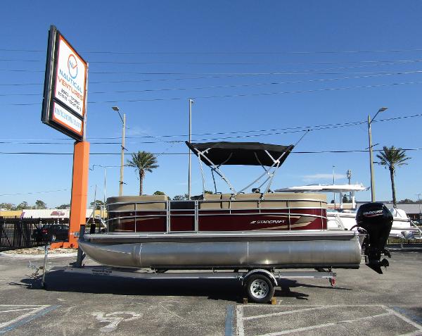 Starcraft LX 20 R 2024 Starcraft LX 20 R pontoon boat on trailer in sunny parking lot.