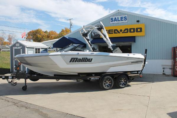 Malibu 21 LX 2025 Malibu 21 LX boat on trailer outside dealership.