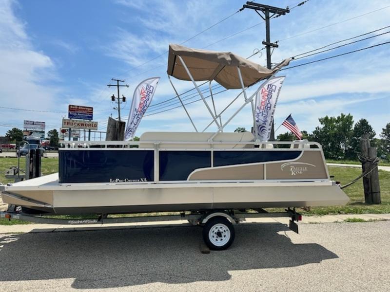 Paddle King Lo Pro Cruiser XL 2026 Paddle King Lo Pro Cruiser XL pontoon boat on trailer, with canopy and flags.