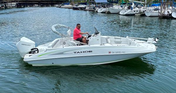 Tahoe 2150 CC 2022 Tahoe 2150 CC boat cruising on a lake with a person at the helm.