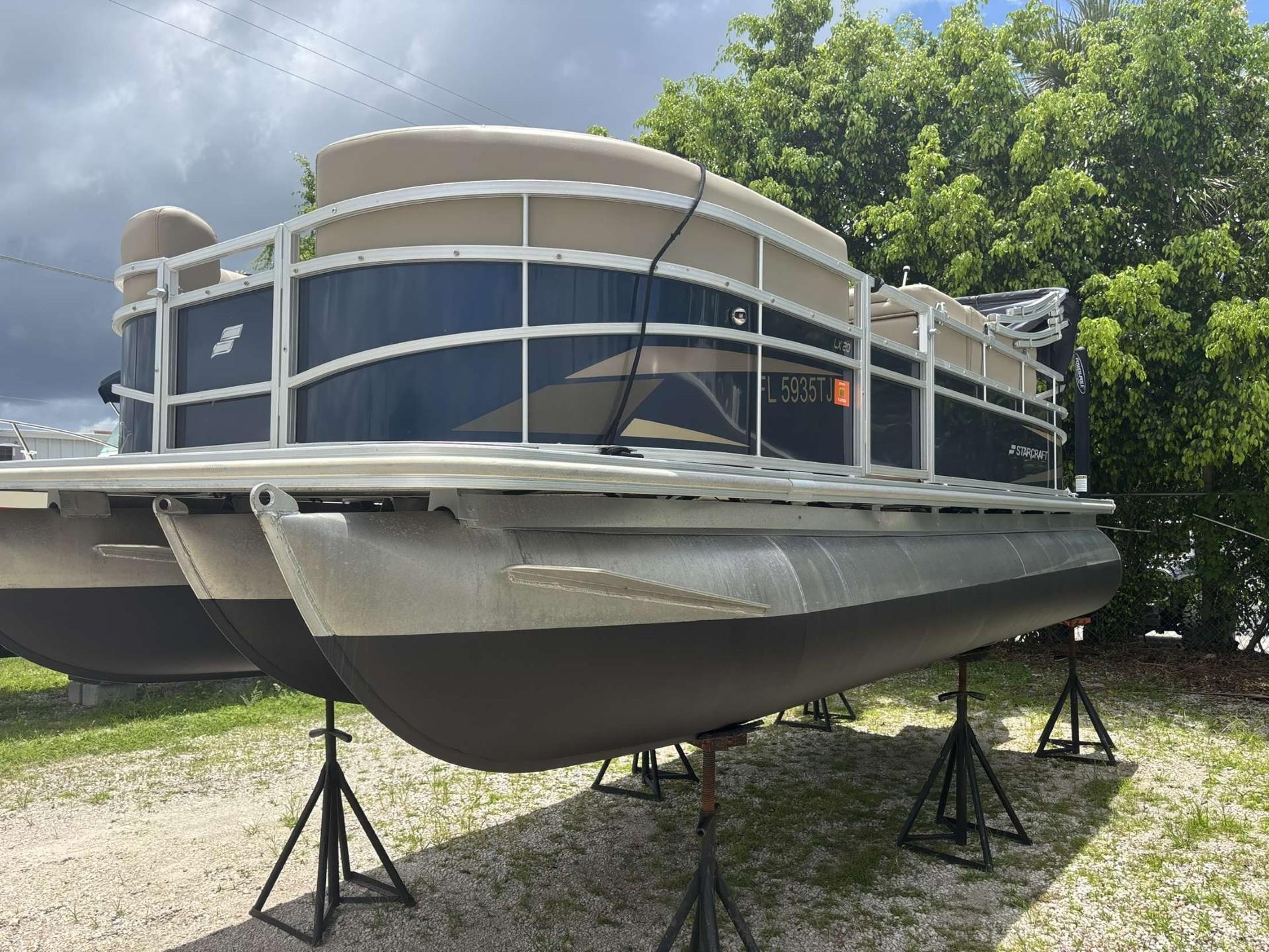 Starcraft LX 20 R 2022 Starcraft LX 20 R pontoon boat on stands, under cloudy sky.