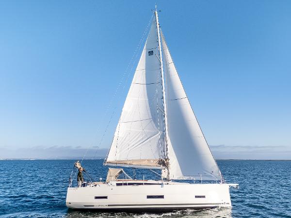 Dufour 390 2023 Dufour 390 sailboat cruising on open water under clear blue skies.