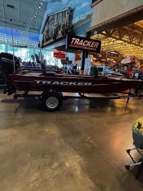 Tracker Panfish 17 2025 Tracker Panfish 17 boat displayed indoors at a showroom with various boating equipment.