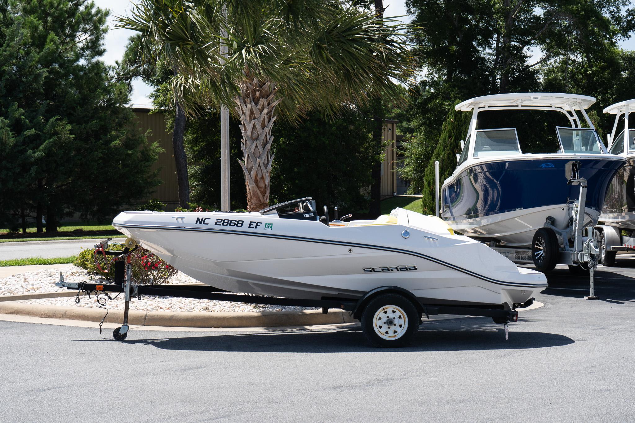 Scarab 165 G 2017 Scarab 165 G boat on trailer, parked outdoors near palm trees.