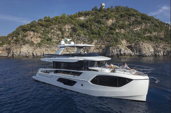 Absolute Navetta 64 2025 Absolute Navetta 64 yacht cruising near rocky coastline.