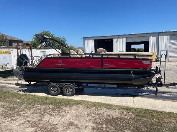Regency 230 LE3 Sport 2024 Regency 230 LE3 Sport pontoon boat on trailer, parked outdoors.