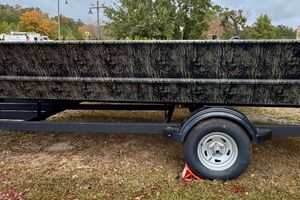Tracker Grizzly 2072 Utility 2026 Tracker Grizzly 2072 Utility boat on trailer, camo design, parked on grass.