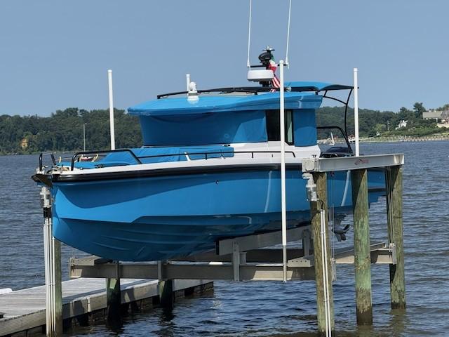 Axopar 37 Cross Cabin 2023 Axopar 37 Cross Cabin boat in vibrant blue, docked on a lift by the water.