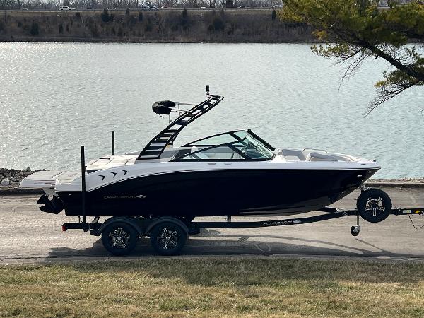Chaparral 21 SSi 2025 Chaparral 21 SSi boat on trailer by a lake, side view.