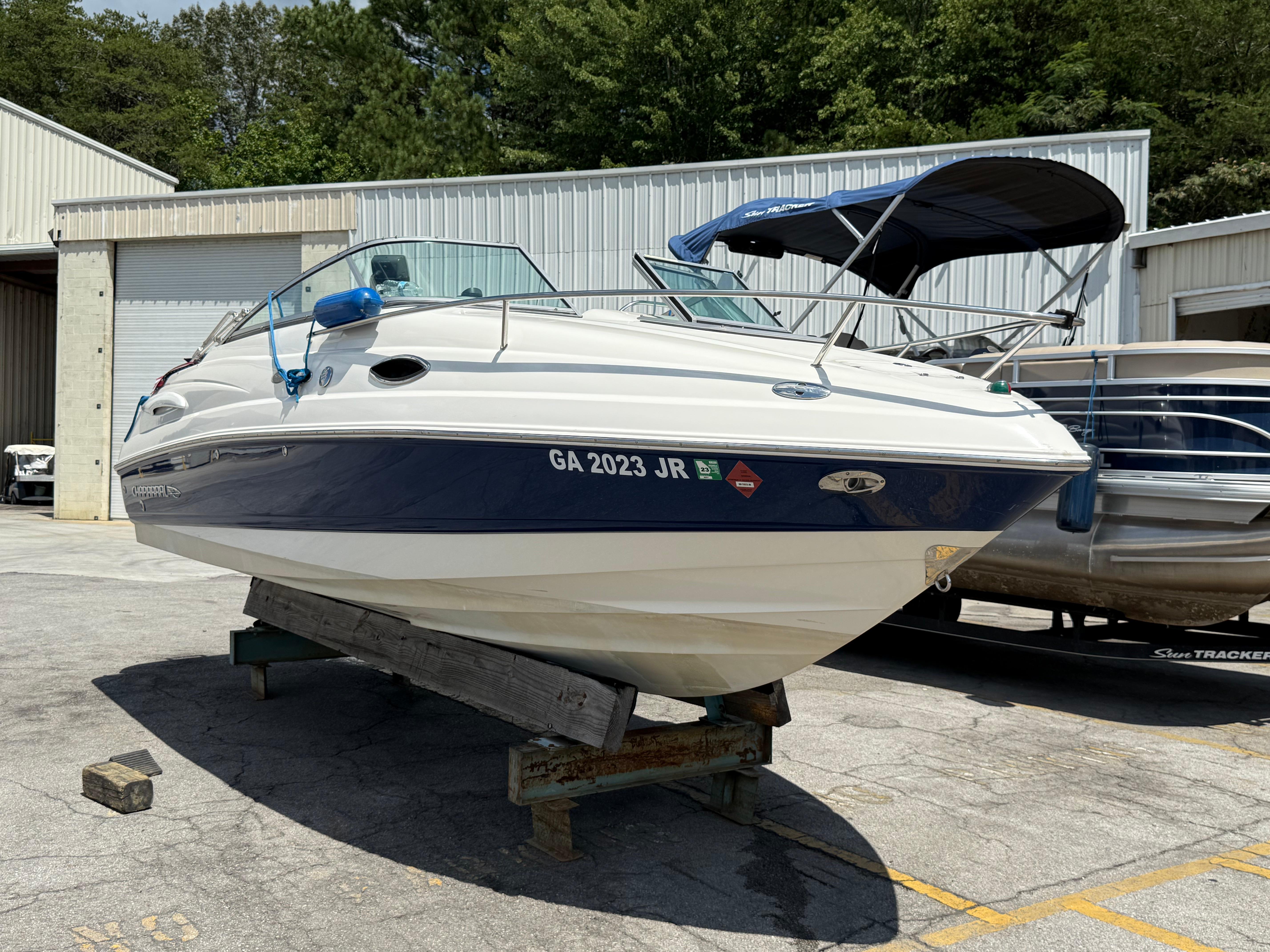 Chaparral 215 SSi 2007 Chaparral 215 SSi boat on a stand, parked outdoors near a warehouse.