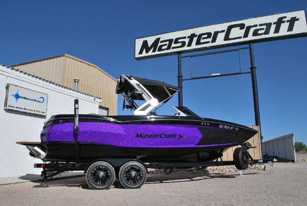MasterCraft XStar S 2023 MasterCraft XStar S boat with purple accents on a trailer, displayed outdoors.