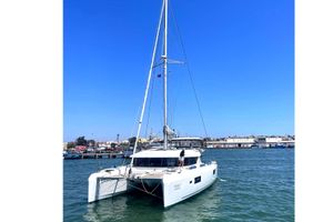 Lagoon 42 2020 Lagoon 42 catamaran sailing in a harbor under clear blue skies.