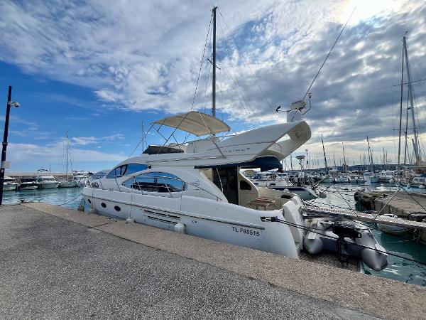 Azimut 46 2004 Azimut 46 yacht docked at a marina under a partly cloudy sky.